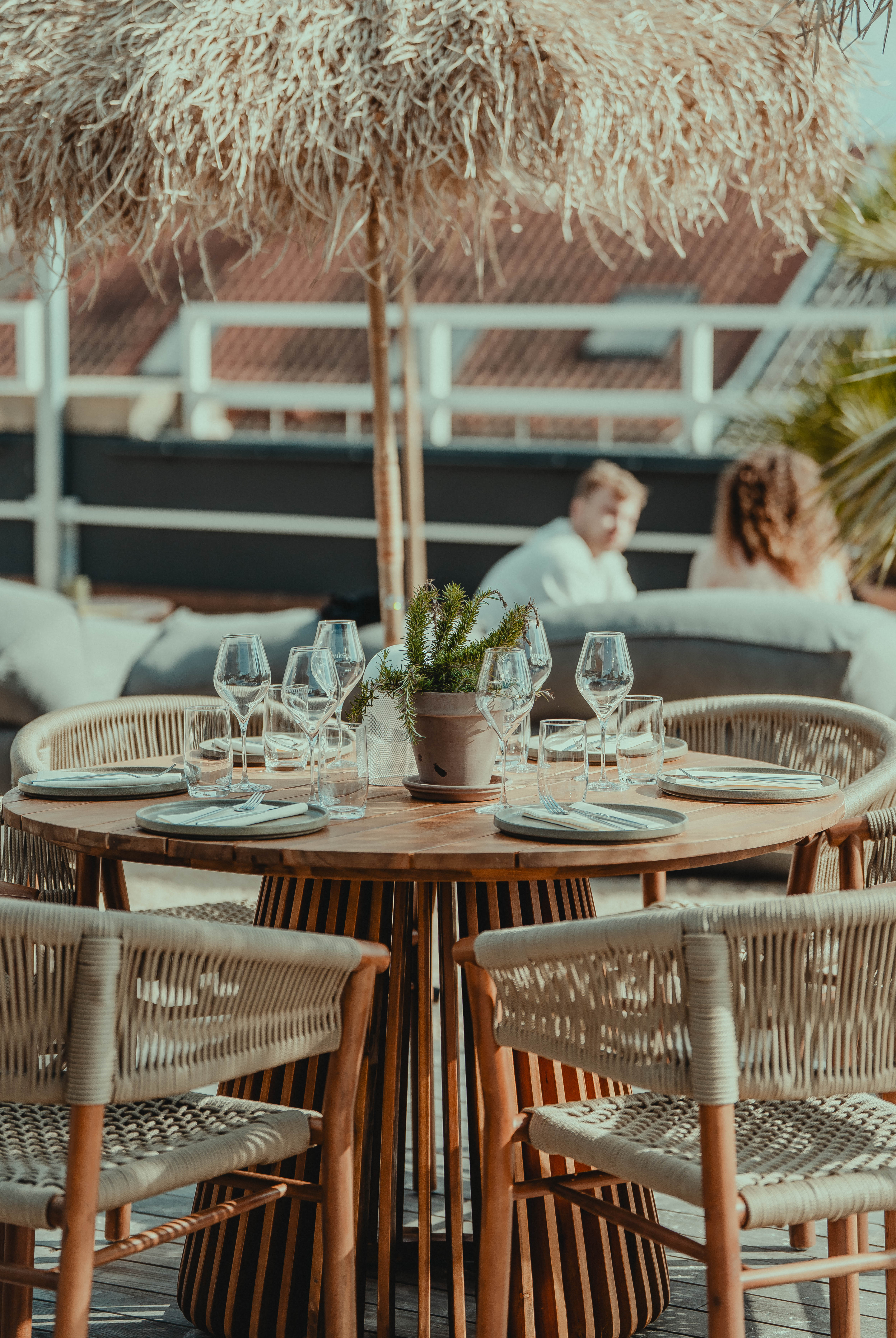 Loungedeck — Tisch unter Strohschirm mit Sofas